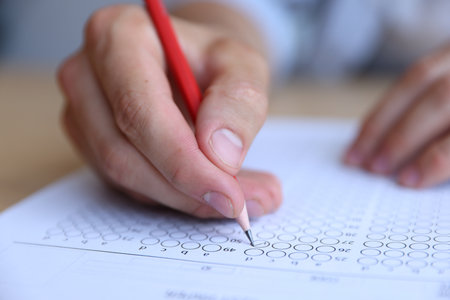 Student filling out multiple choice test at table, closeup. Passing examの写真素材