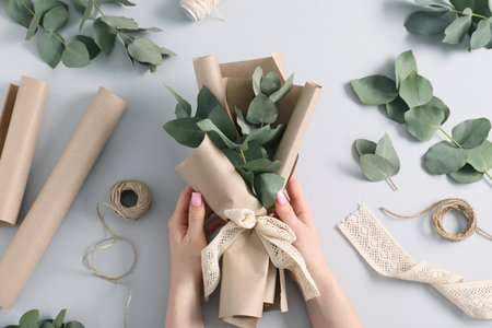Florist making beautiful bouquet of eucalyptus branches at white table, top viewの写真素材