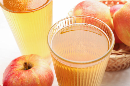 Delicious cider in glasses and red apples on white table, closeupの写真素材