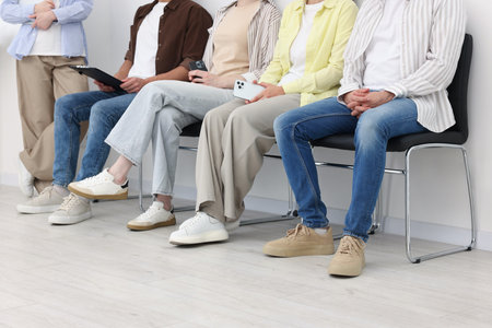People waiting in queue on chairs indoors, closeupの写真素材