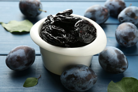 Dried prunes and fresh plums on blue wooden table, closeupの写真素材