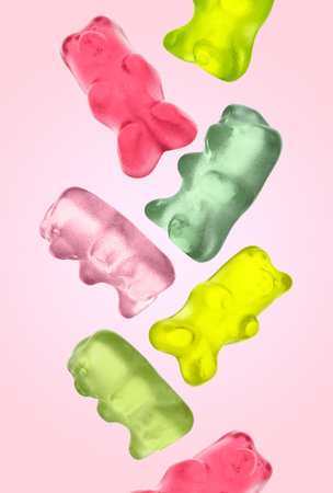 Sweet jelly candies in shape of bear falling against pink backgroundの写真素材