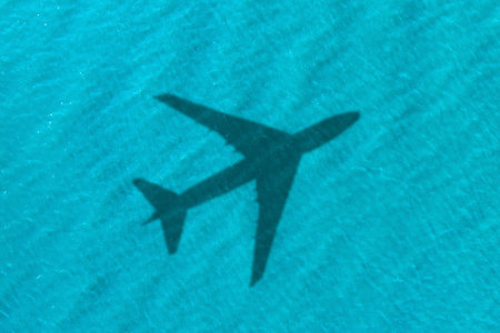 Flying airplane casting shadow on water, top viewの写真素材