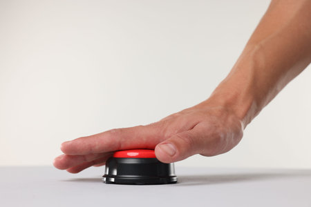 Man pressing red button on white background, closeup