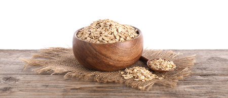 Oat flakes in bowl and spoon on wooden table against white background