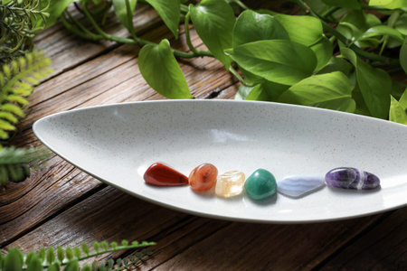 Different natural mineral stones and green leaves on wooden table, closeup