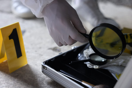 Forensic expert with magnifying glass working at crime scene indoors, closeup