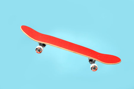Red skateboard in air against light blue background