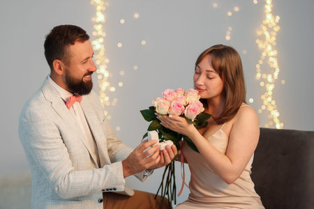 Man with engagement ring making marriage proposal to his girlfriend on light gray background with blurred lights, bokeh effectの写真素材