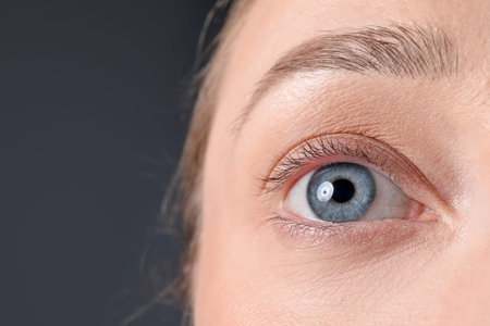 Woman with beautiful eyes on gray background, closeup. Space for textの写真素材