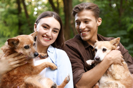 Happy couple holding their cute dogs outdoorsの写真素材