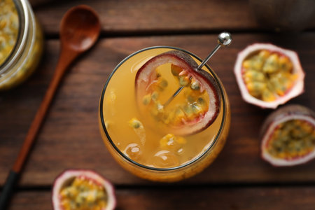 Tasty passion fruit drink in glass and fresh fruits on wooden table, flat lay