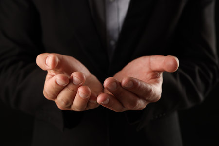 Man holding something on black background, closeup