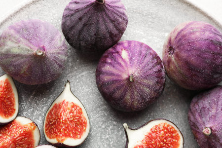 Whole and cut figs on gray plate, top view