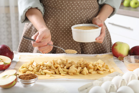 Woman making delicious apple strudel at white table in kitchen, closeupの写真素材