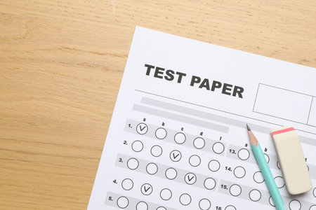 Answer sheet, eraser and pencil on wooden table, flat lay. Student passing examの写真素材
