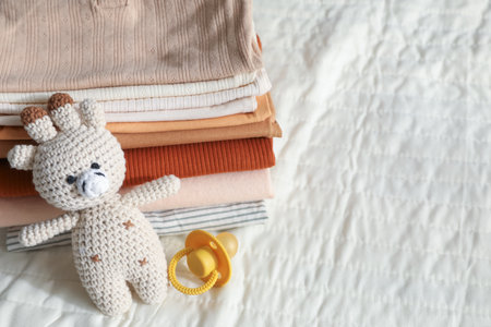 Stack of clean baby clothes and accessories on bed, closeup. Space for textの写真素材