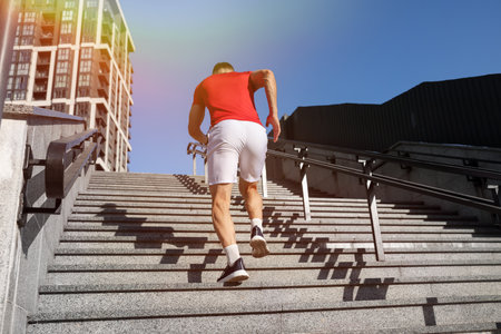 Man in sportswear running up on stairs outdoors, low angle viewの写真素材