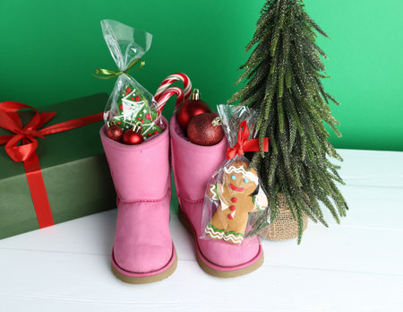 Happy Saint Nicholas day. Boots with festive decor, sweets and gift box on white wooden table