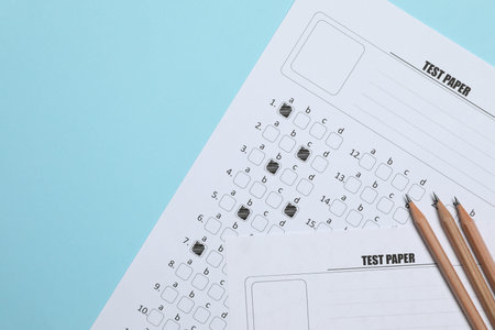 Answer sheets and pencils on light blue background, flat lay. Student passing exam