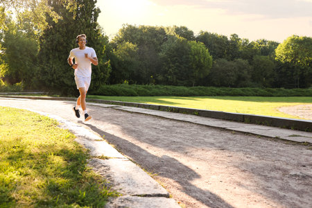 Happy man with headphones running in park