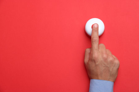 Man pressing button on red background, top view. Space for text