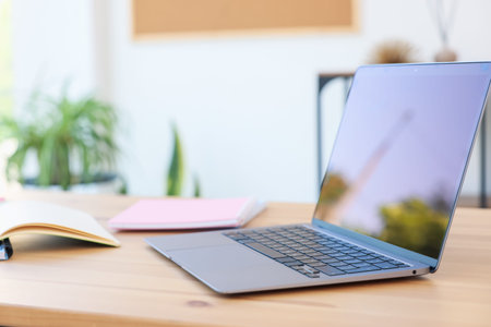 Home workspace. Modern laptop and stationery on wooden desk indoors, closeup