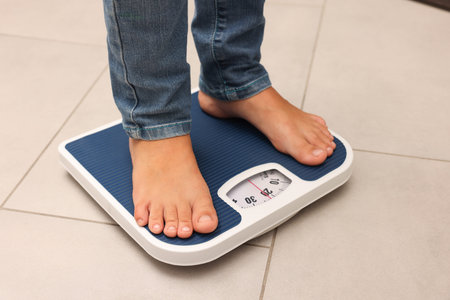 Little boy standing on scales indoors, closeup