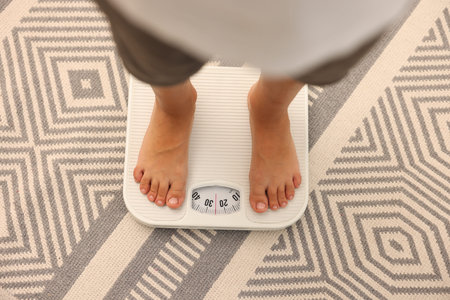 Little boy standing on scales indoors, top view