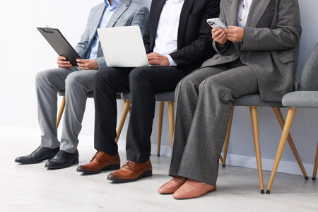 People waiting in queue on chairs indoors, closeup