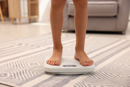 Little boy standing on scales indoors, closeup