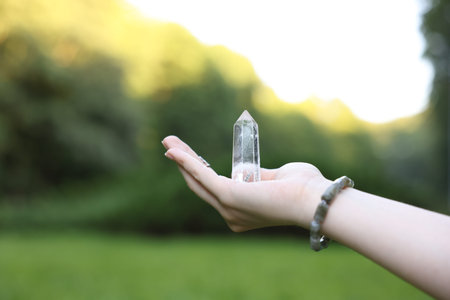 Woman meditating with crystal outdoors, closeup