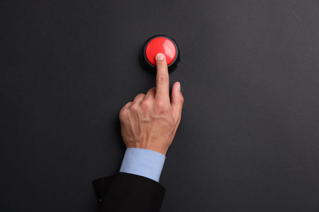 Man pressing button on black background, top view