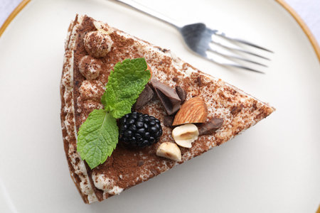 Piece of crepe cake with cocoa powder, chocolate, nuts and blackberry served on table, top viewの写真素材
