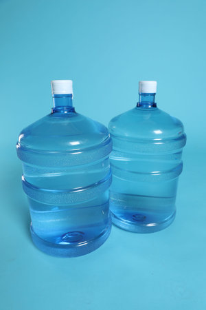 Cooler bottles with water on light blue background