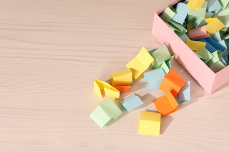 Color paper pieces on light wooden table, above view. Space for text