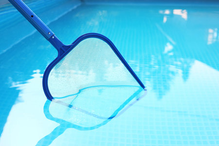 Cleaning swimming pool with skimmer net, closeup