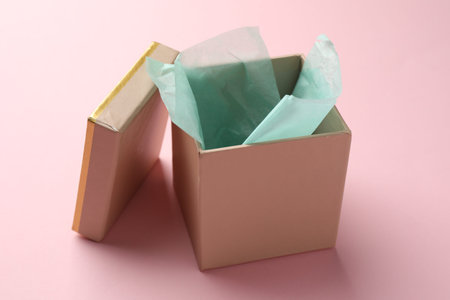 Open gift box with lid on pink background, closeup