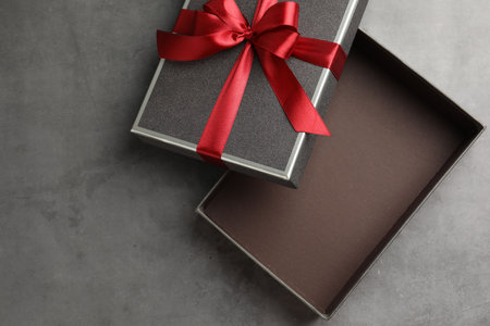 Opened gift box with beautiful lid on gray table, top view