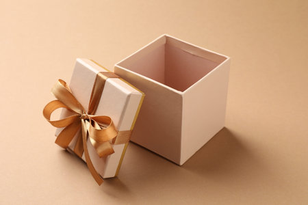 Opened gift box with beautiful lid on beige background, closeup