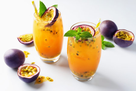 Tasty passion fruit drink with mint in glasses and fresh fruits on white tableの写真素材