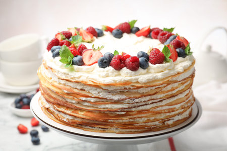 Delicious crepe cake with fresh berries on white table, closeup
