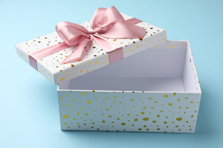 Opened gift box with beautiful lid on light blue background, closeup