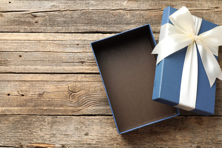 Opened gift box with beautiful lid on wooden table, top view. Space for text