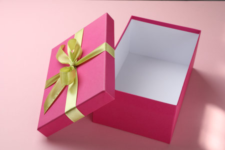 Open gift box with beautiful lid on pink background