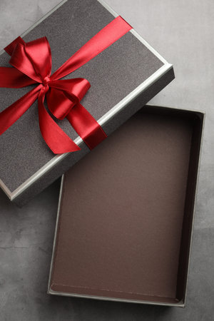 Opened gift box with beautiful lid on gray table, top view