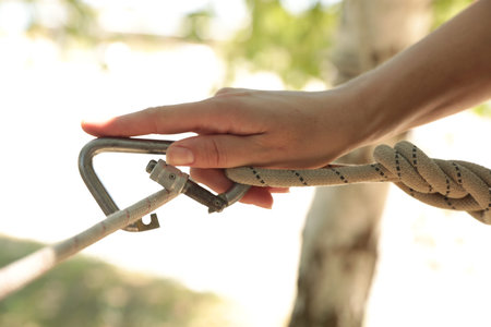 Woman using screw lock carabiner during training outdoors, closeup