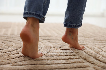 Person walking barefoot on soft beige carpet at home, closeupの写真素材