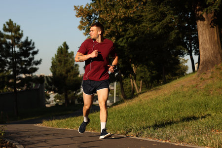 Athletic young man in sportswear running outdoors, space for text