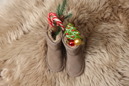 Saint Nicholas Day tradition. Child's boots with treats on fur rug, above view